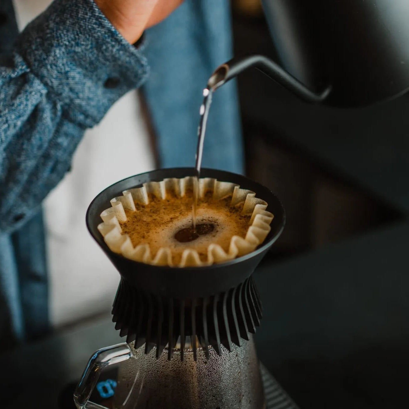Coffee being poured into a Kode coffee brewer with a blurred background